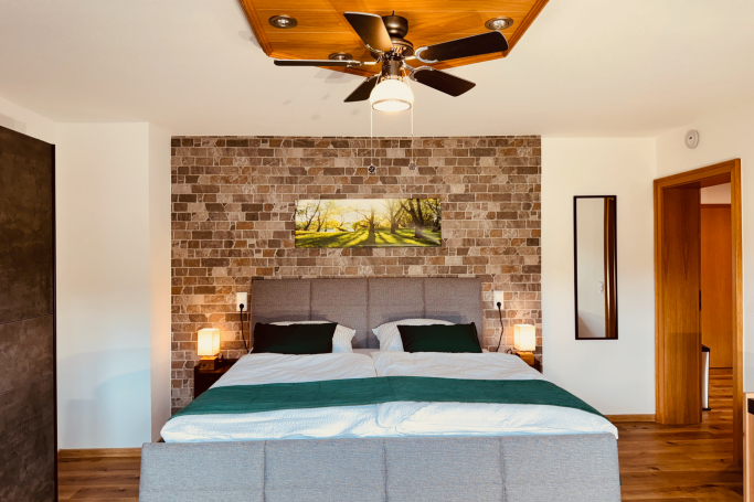 Schlafzimmer mit Boxspringbett Ferienhaus Taufstein Schlafzimmer im Ferienhaus Taufstein mit komfortablem Boxspringbett und Natursteinwand